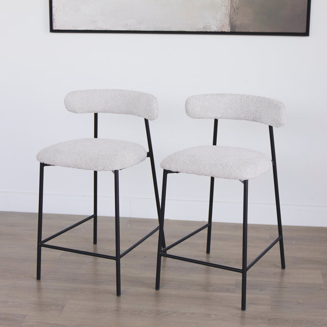 Paire de tabourets en tissu crème bouclé avec pieds metalliques noirs.