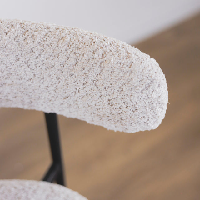 Image rapprochée du dossier d'une paire de tabourets en tissu crème bouclé avec pieds metalliques noirs.