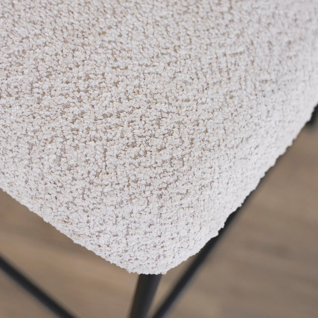 Image rapprochée du tissu d'une paire de tabourets en tissu crème bouclé avec pieds metalliques noirs.
