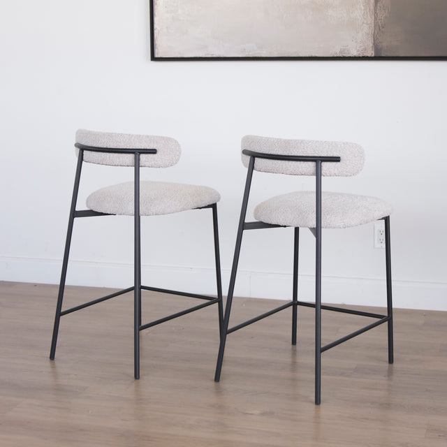 Paire de tabourets en tissu crème bouclé avec pieds metalliques noirs.