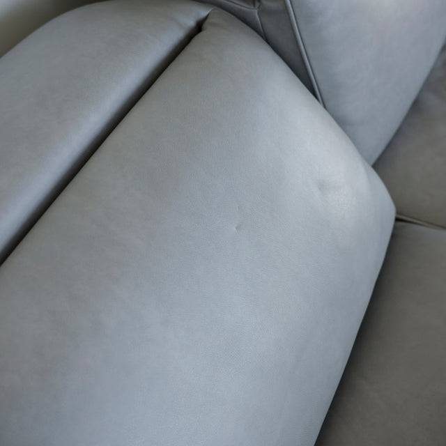 Image rapprochée d'un Canape avec chaise longue droite en cuir gris clair avec pieds noirs.