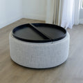 Pouf rond en tissu bouclé gris  avec plateau noir amovible sur sol en bois clair.