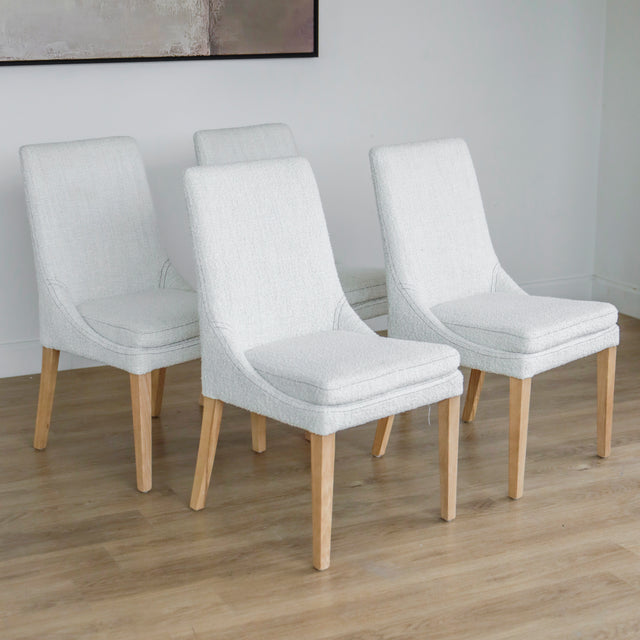 ensemble de chaises modernes en tissu bouclé ivoire avec pieds en bois pâle sur sol en parquet.