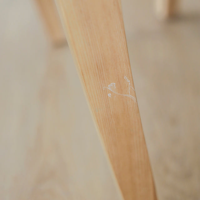 image rapprochée d'un ensemble de chaises modernes en tissu bouclé ivoire avec pieds en bois pâle avec défaut d'un accroc sur une patte.