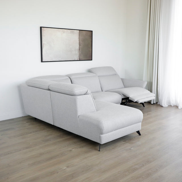 Modulaire inclinable moderne en tissu gris clair avec pieds metalliques noirs sur parquet clair.