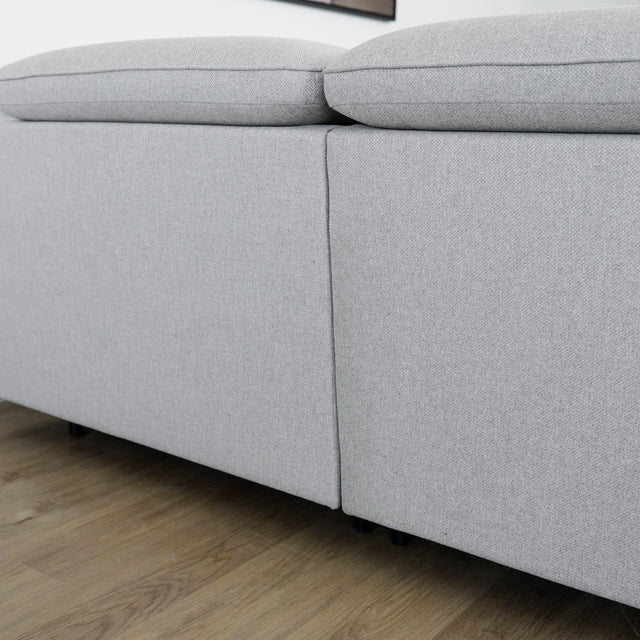 Modulaire inclinable moderne en tissu gris clair avec pieds metalliques noirs sur parquet clair.