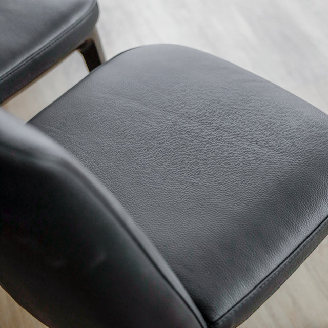 image rapprochée d'un ensemble de six chaises modernes en cuir noir avec pieds en bois noir sur parquet clair.