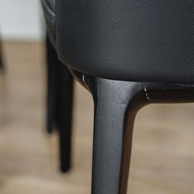 image rapprochée d'un ensemble de six chaises modernes en cuir noir avec pieds en bois noir sur parquet clair.