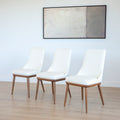 Trois chaises modernes en cuir blanc avec pieds en bois couleur noyer, design pure pour salle a manger contemporaine.
