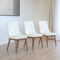 Trois chaises modernes en cuir blanc avec pieds en bois couleur noyer, design pure pour salle a manger contemporaine avec cercles indquant les défauts.