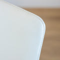 Image rapprochée d'une chaise moderne en cuir blanc avec pieds en bois couleur noyer, design pure pour salle a manger contemporaine.