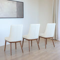 Trois chaises modernes en cuir blanc avec pieds en bois couleur noyer, design pure pour salle a manger contemporaine.