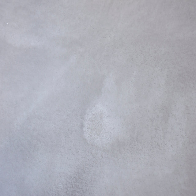 Image rapprochée table rectangulaire en beton avec pieds en metal noir en X, style industriel moderne.