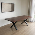 Table rectangulaire en bois fonce avec pieds en metal noir en X, style industriel contemporain.