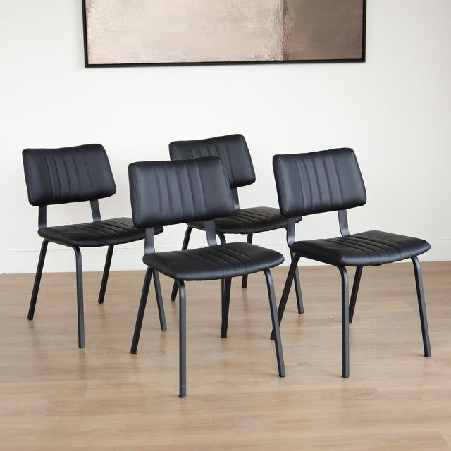 Quatre chaises noires en simili cuir avec pieds en metal, design moderne pour salle a manger.