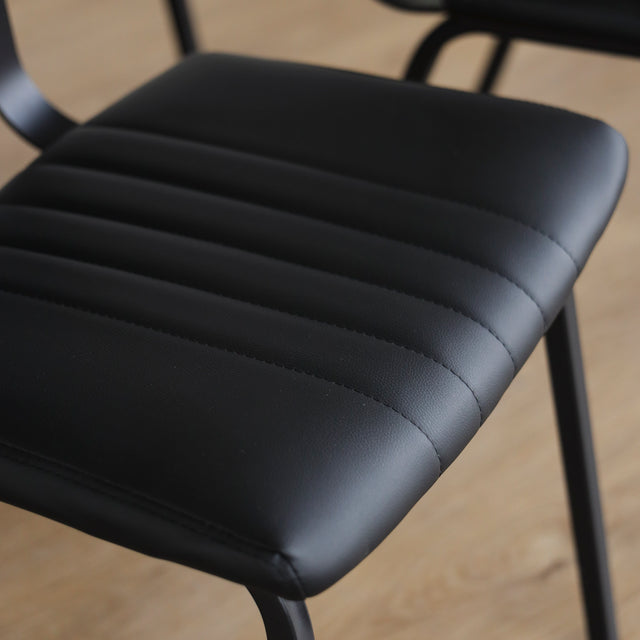 Quatre chaises noires en simili cuir avec pieds en metal, design moderne pour salle a manger.