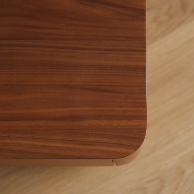 Image rapprochée d'une table de chevet moderne en bois noyer avec coins arrondis et tiroir integre.