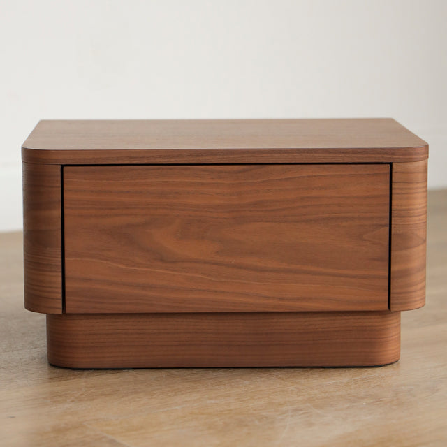 Table de chevet moderne en bois noyer avec coins arrondis et tiroir integre.