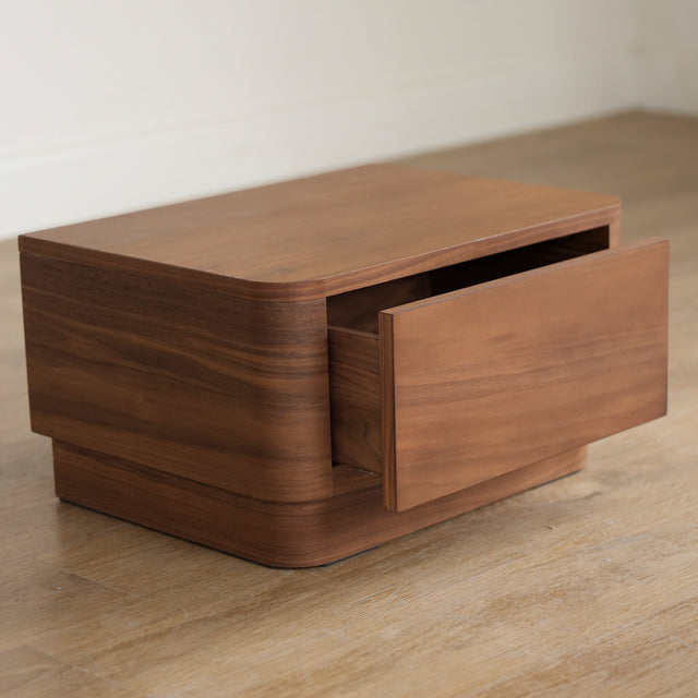 Table de chevet moderne en bois noyer avec coins arrondis et tiroir integre.