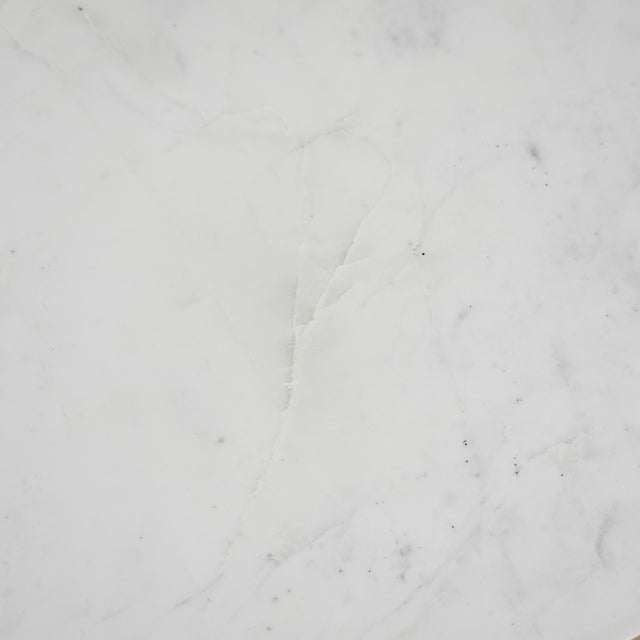 Image rapprochée d'une Table basse ronde avec plateau en marbre blanc et structure en metal noir, style moderne et minimaliste.