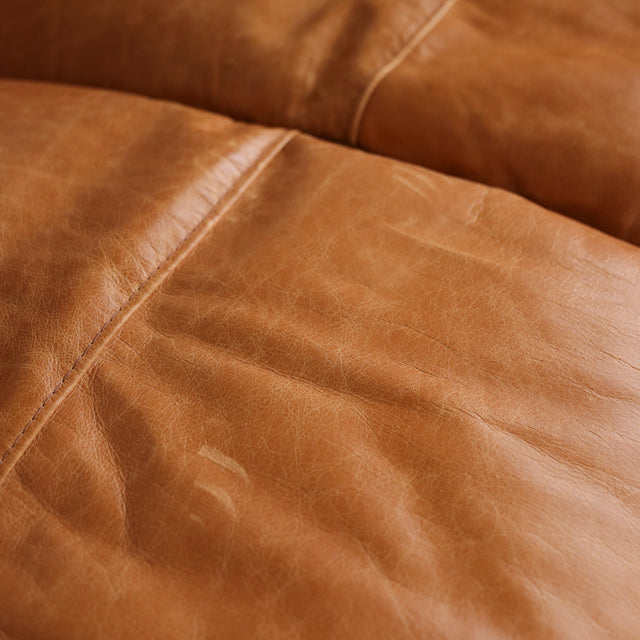 Image rapprochée d'un canape inclinable en cuir brandy au design contemporain avec accoudoirs larges et assises confortables.