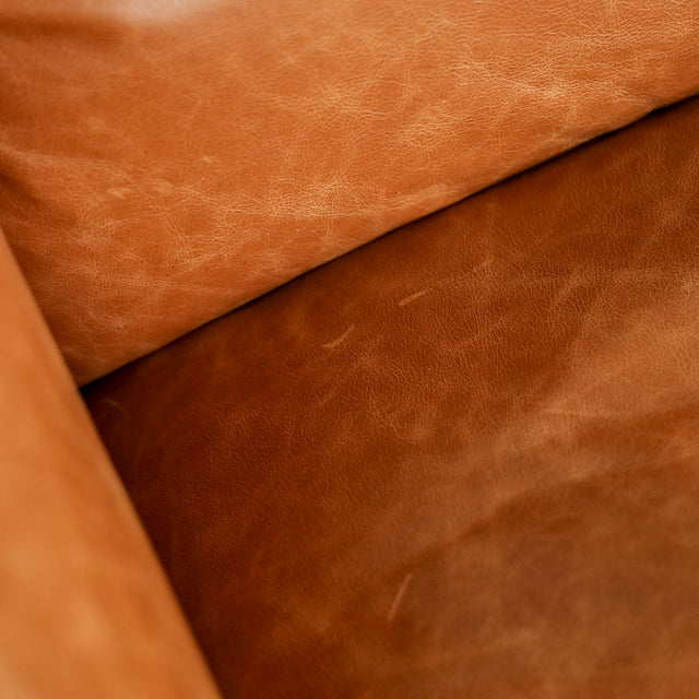 Image rapprochée d'un canape inclinable en cuir brandy au design contemporain avec accoudoirs larges et assises confortables.