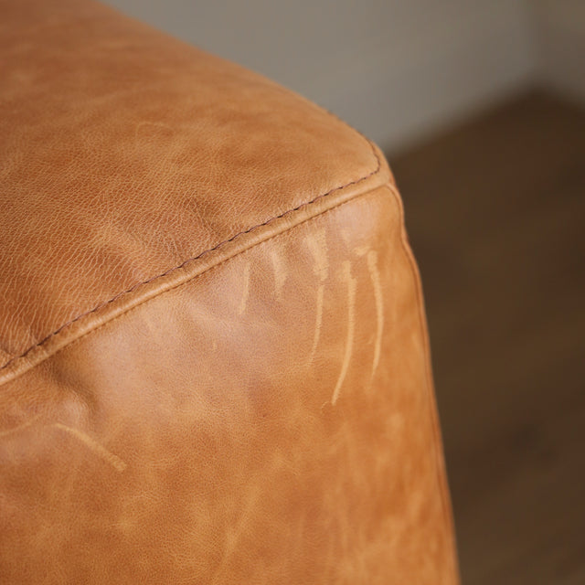 Image rapprochée d'un canape inclinable en cuir brandy au design contemporain avec accoudoirs larges et assises confortables.