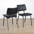 Deux chaises noires en simili cuir avec structure en metal, design industriel moderne.