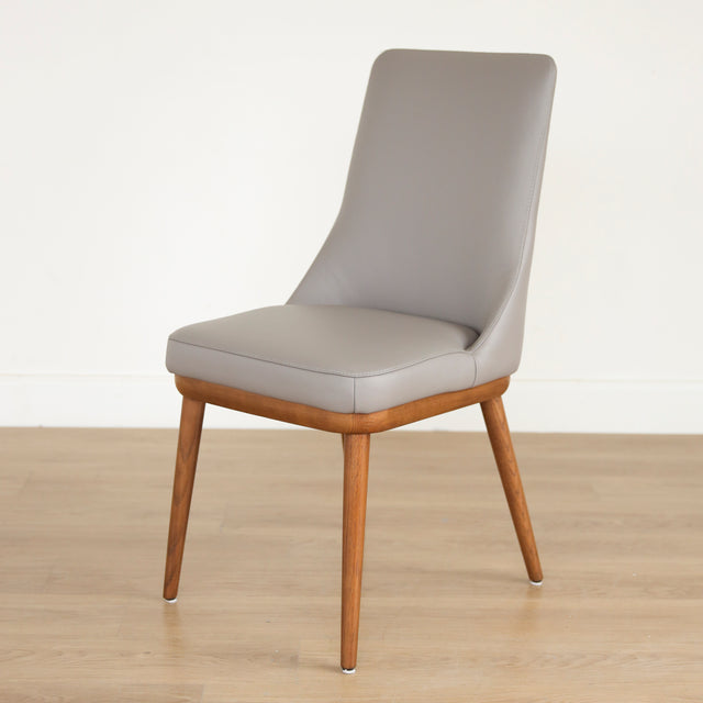 Chaise moderne en cuir gris avec assise rembourree et pieds en bois.
