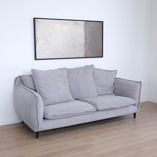 Canapé gris moderne avec coussins moelleux dans un salon minimaliste.