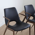 ensemble de chaises noires modernes avec accoudoirs en métal imitation bois et assise ajouree.