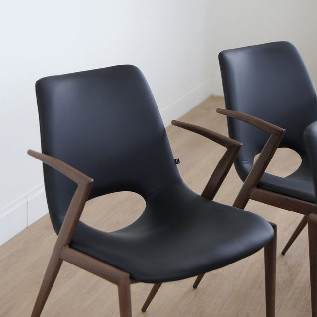 ensemble de chaises noires modernes avec accoudoirs en métal imitation bois et assise ajouree.