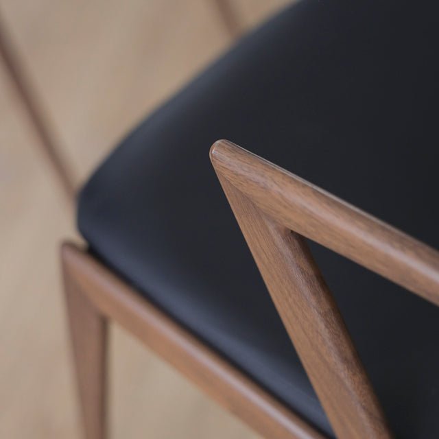 ensemble de chaises noires modernes avec accoudoirs en métal imitation bois et assise ajouree.