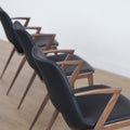 ensemble de chaises noires modernes avec accoudoirs en métal imitation bois et assise ajouree.