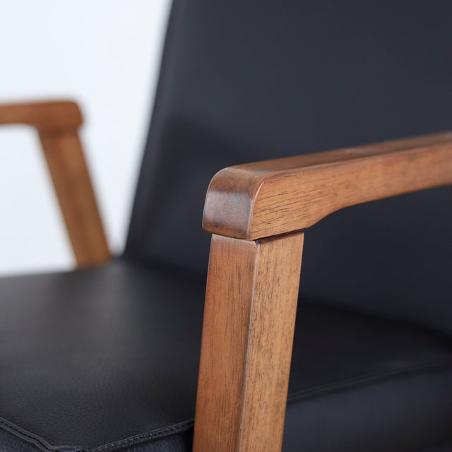 image rapprochée chaise noire avec assise rembourree et structure en bois naturel.