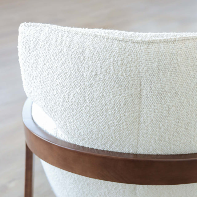 Fauteuil moderne en tissu bouclé ivoire avec structure en bois, idéal pour salon contemporain lumineux.