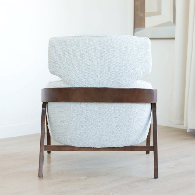 Fauteuil moderne en tissu bouclé ivoire avec structure en bois, idéal pour salon contemporain lumineux.