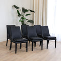 Lot de 4 chaises de cuisine, cuir végane noir, pattes noires, avec coutures contrastantes dans un décor moderne et lumineux. 
