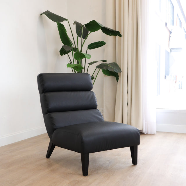 Fauteuil  en cuir végane noir avec dossier matelassé et pieds inclinés, style moderne pour salon. 