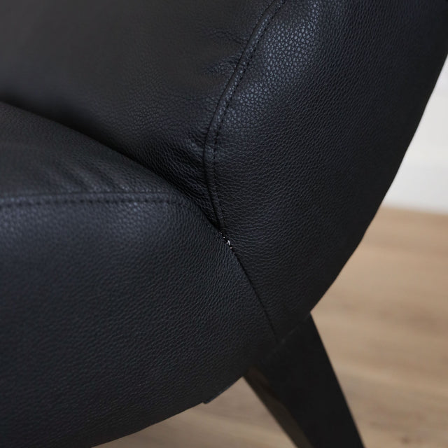 Fauteuil  en cuir végane noir avec dossier matelassé et pieds inclinés, style moderne pour salon. 