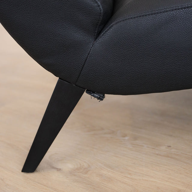 Fauteuil  en cuir végane noir avec dossier matelassé et pieds inclinés, style moderne pour salon. 