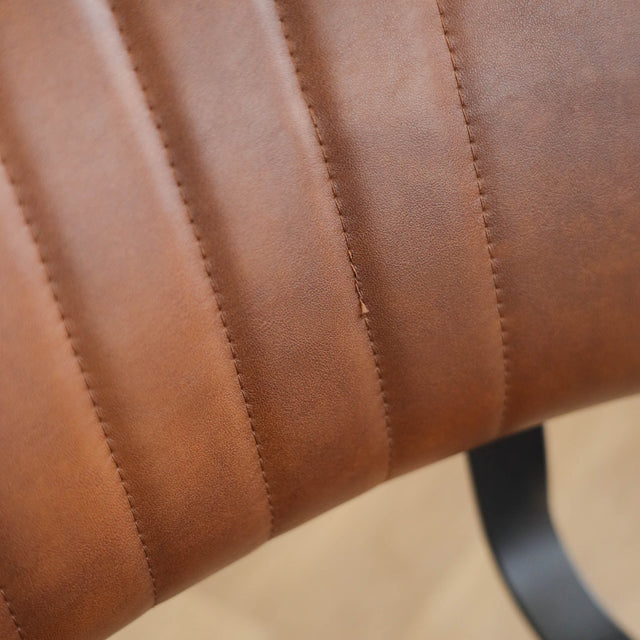 Deux chaises de salle à manger en cuir végane cognac, piètement métal noir, style industriel moderne.