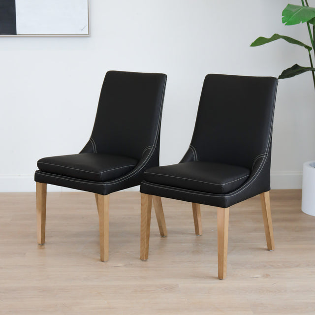 Lot de deux  chaises de salle à manger en cuir végane noir avec pattes en bois pâle, design moderne et élégant.