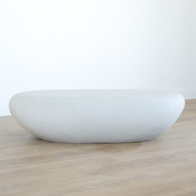 Table basse design en béton blanc, forme galet organique, idéale pour salon moderne et épuré.