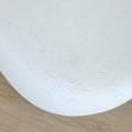Table basse design en béton blanc, forme galet organique, idéale pour salon moderne et épuré.