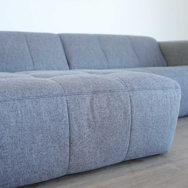 Modulaire deux places en tissu gris foncé avec chaise longue gauche, design moderne et lignes épurées pour salon contemporain.