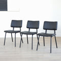Lot de trois chaises de salle à manger noires en cuir végane noir avec piètement en métal noir, style moderne minimaliste.