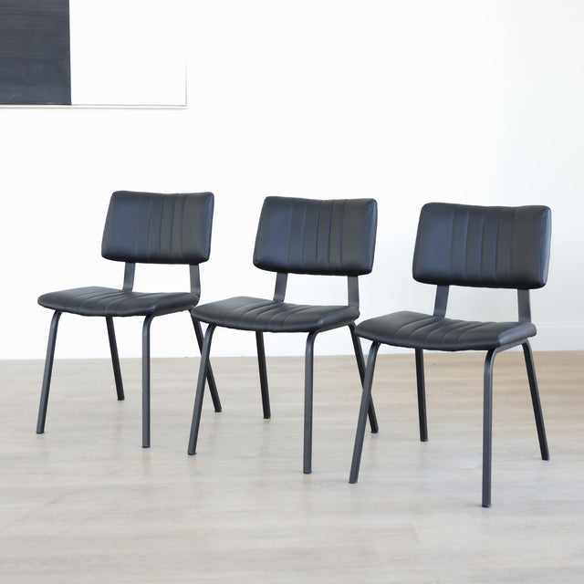 Lot de trois chaises de salle à manger noires en cuir végane noir avec piètement en métal noir, style moderne minimaliste.