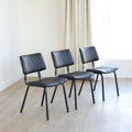 Lot de trois chaises de salle à manger noires en cuir végane noir avec piètement en métal noir, style moderne minimaliste.
