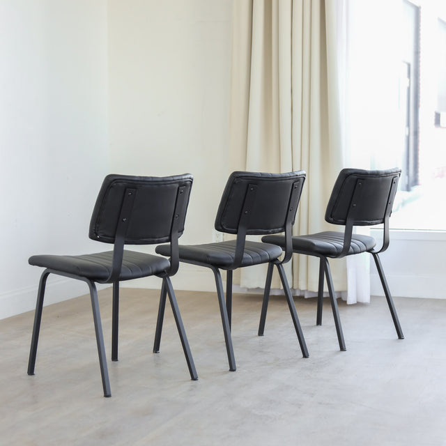 Lot de trois chaises de salle à manger noires en cuir végane noir avec piètement en métal noir, style moderne minimaliste.